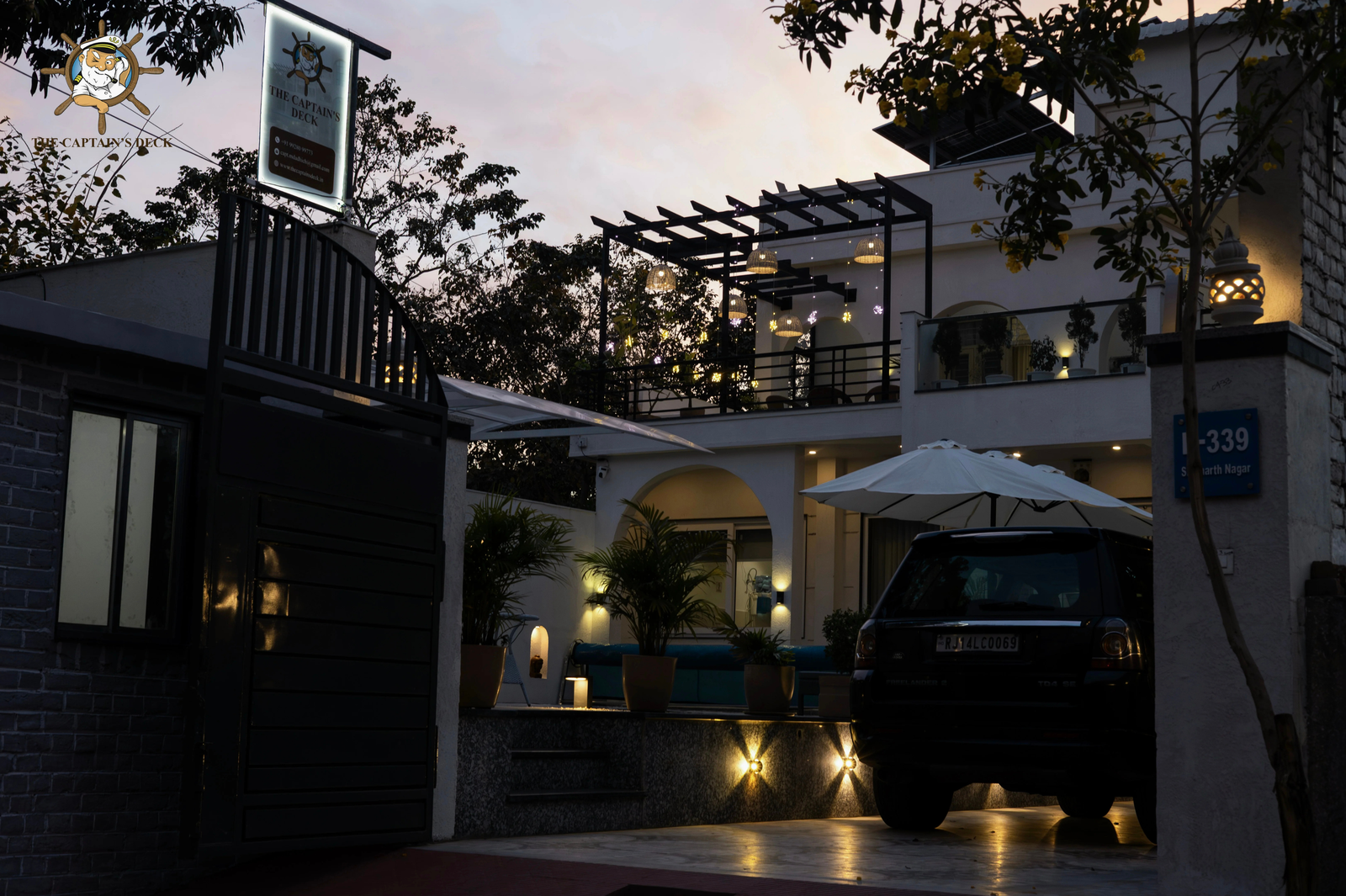 Panoramic nighttime view of the villa with garden lighting