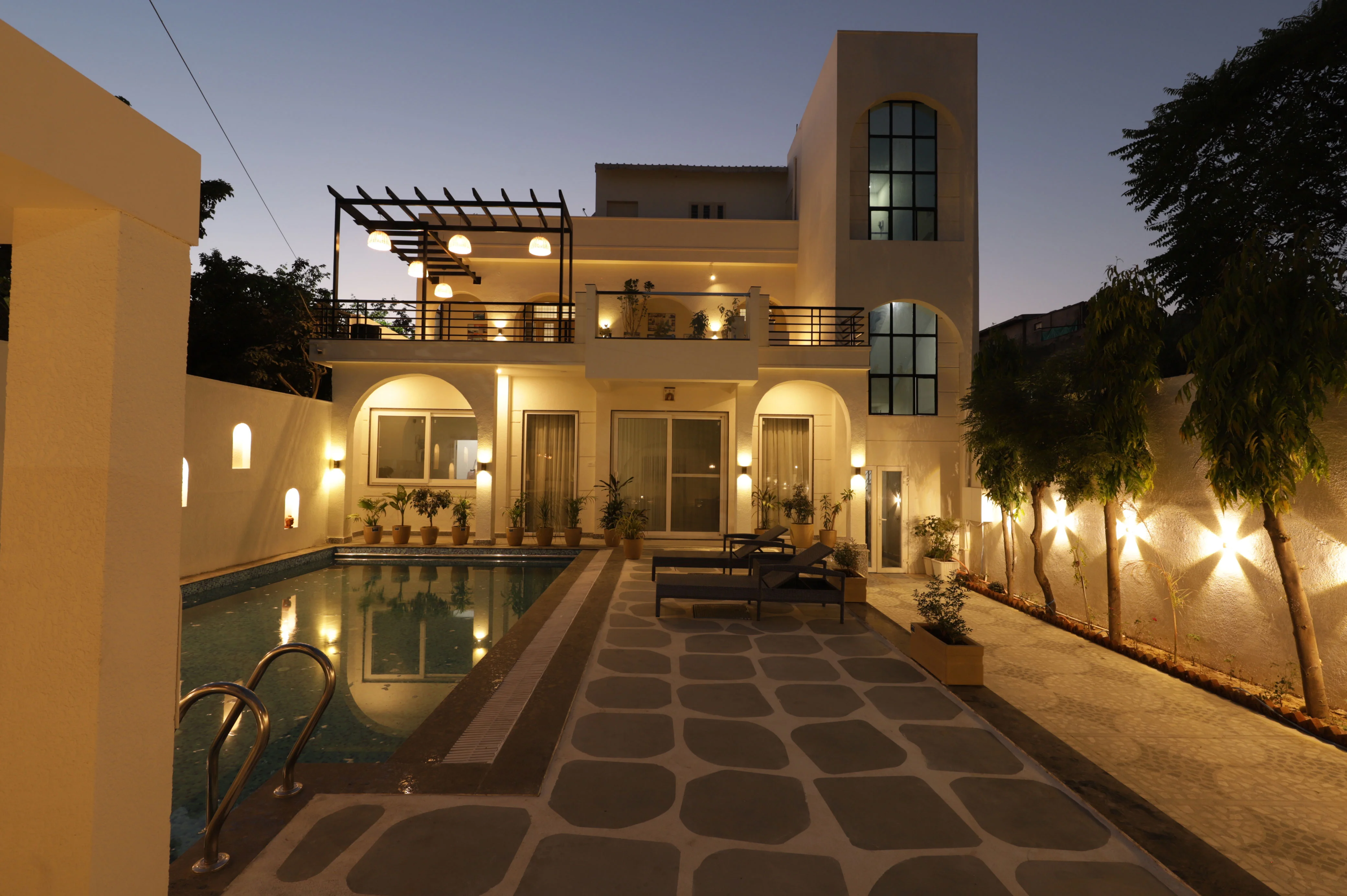 Panoramic nighttime view of the villa with garden lighting